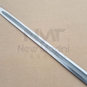 May include: A close-up of a silver sword blade with a patterned design. The blade is sharp and pointed.