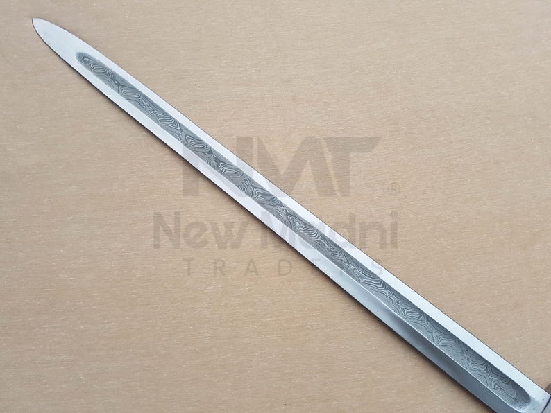May include: A close-up of a silver sword blade with a patterned design. The blade is sharp and pointed.