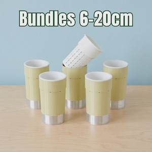 Op de afbeelding: Een set van vijf cilindrische houders met lichtgele buitenzijden, witte binnenzijden en zilverkleurige metalen bodems. Eén houder is voorzien van een witte inzet met sleuven. De tekst Bundles 6-20cm staat bovenaan de afbeelding.