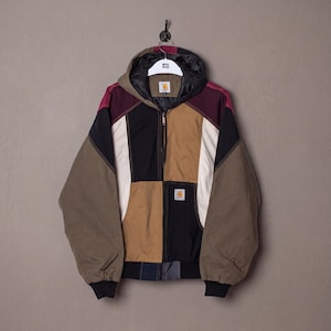 Puede incluir: Chaqueta con capucha multicolor con diseño de patchwork. La chaqueta presenta paneles marrones, negros, beige, blancos y burdeos. Tiene cremallera frontal, capucha y un pequeño parche con el logo. Colgada de un gancho negro sobre un fondo neutro.