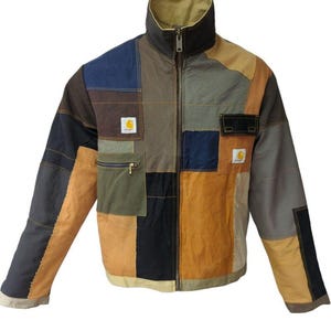May include: A patchwork jacket in various colors, including tan, navy, black, and olive green. The jacket features a high collar, a full-length zipper, and multiple pockets. The Carhartt logo is visible on the chest.