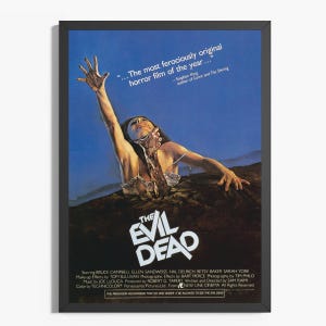 May include: A framed film poster for The Evil Dead featuring a person emerging from dark earth against a blue sky. The text reads: The Evil Dead, ...The most ferociously original horror film of the year..., and lists the cast and production crew.