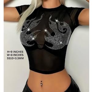 Pode incluir: Top curto de malha preta com mangas curtas e gola redonda. A parte superior apresenta um design de chama feito de strass brilhantes. O texto na imagem diz: H=23 cm, L=20 cm, SS10=3,3 mm. Uma peça elegante e atraente.