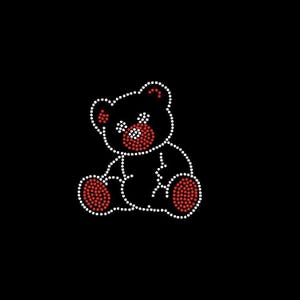 May include: A black graphic of a teddy bear made of white and red rhinestones. The bear is outlined in white rhinestones, with red rhinestones filling in the ears, nose, and paws. The background is solid black.