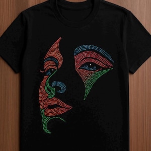 Könnte beinhalten: Schwarzes T-Shirt mit einem Gesichtsmotiv aus farbigen Punkten. Das Design verwendet rote, grüne und blaue Punkte, um die Umrisse eines Gesichts zu erstellen. Das T-Shirt besteht aus einem weichen Material und ist für den Freizeitgebrauch geeignet.