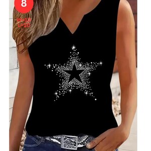 May include: Black sleeveless top with a V-neck and a large star design made of white rhinestones. The top is paired with blue jeans and a silver and black belt. The number 8 is visible in a red circle in the upper left corner.