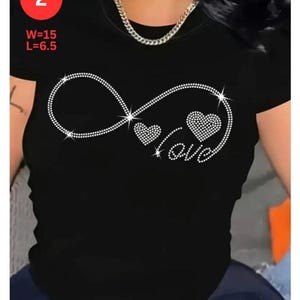 May include: Black short-sleeved t-shirt with a rhinestone infinity symbol design, two rhinestone hearts, and the word "love". The shirt has the measurements W=15 and L=6.5 in red text in the upper left corner.