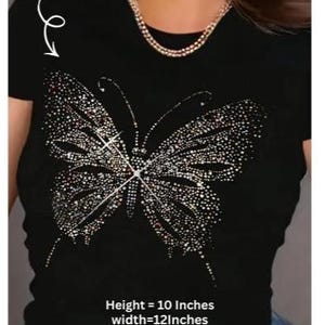 Peut inclure: T-shirt noir orné d'un motif papillon scintillant. Le papillon est composé de nombreux petits ornements brillants. La hauteur du t-shirt est de 25,4 cm, et la largeur est de 30,48 cm.