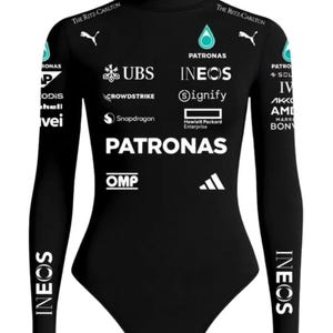 Könnte beinhalten: Ein schwarzer Langarm-Body mit Stehkragen und weißen Sponsorenlogos, darunter Petronas, Ineos, UBS, Crowdstrike, Snapdragon, OMP und The Ritz-Carlton. Das Kleidungsstück zeigt das Puma-Logo auf der Brust und den Ärmeln sowie verschiedene Markenschriftzüge.