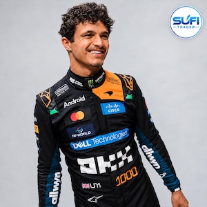 May include: A black and orange racing suit featuring various sponsor logos including Android, Cisco, Dell Technologies, Hilton, and Mastercard. The suit displays the text OKX, 1000, and a small British flag with the initials LM on the chest area.