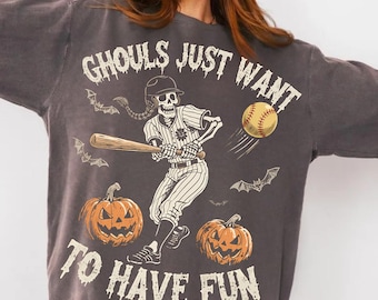 Może przedstawiać: Ciemnoszara bluza z motywem Halloween. Projekt przedstawia szkieletowego gracza w baseball, który wymachuje kijem, piłkę do baseballu, nietoperze i dynie. Tekst brzmi "Ghouls Just Want To Have Fun."