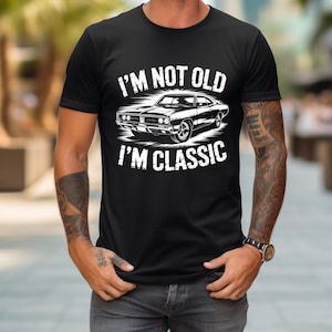 May include: Black t-shirt with a white graphic of a classic car and the text "I'M NOT OLD I'M CLASSIC". The design features a vintage car illustration, perfect for car enthusiasts.