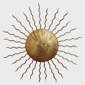 May include: A gold-coloured metal sunburst wall decor. The sun has a textured, circular centre with radiating wavy rays. The metal has a distressed finish, giving it a vintage appearance. This decorative piece is designed for wall mounting.
