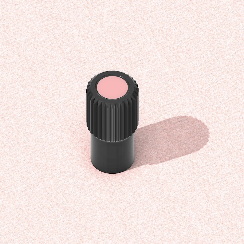 以下が含まれることがあります： 黒い円筒形の物体で、上部に溝があり、中央にピンク色の円があります。物体はピンク色の表面に影を落としています。この物体は美容製品のようです。