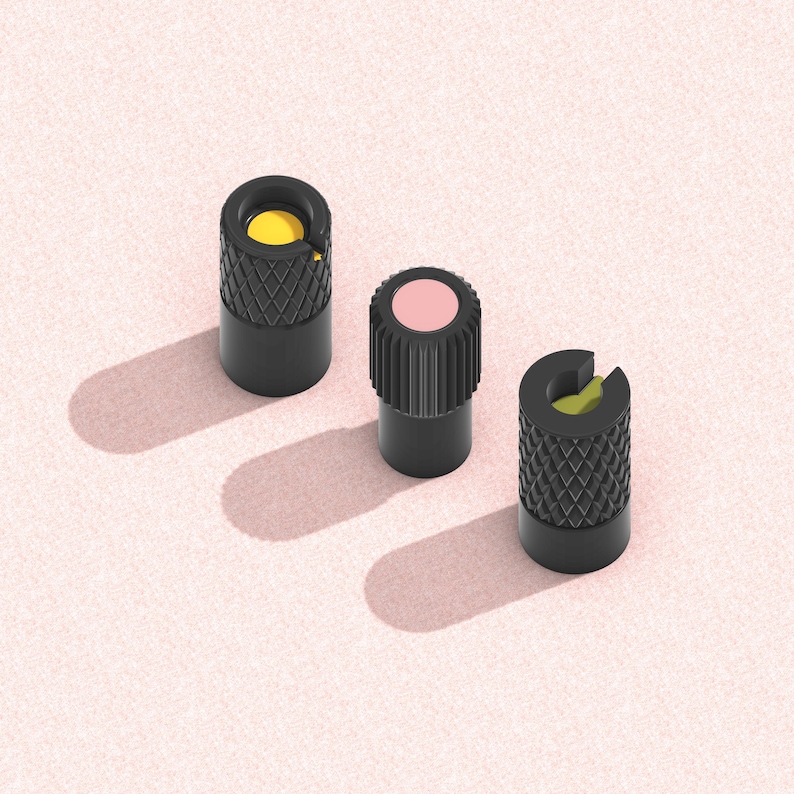 以下が含まれることがあります： ピンク色の背景に、テクスチャ加工された表面と色の付いた上部を持つ3つの黒い円筒形のオブジェクトが配置されています。1つは黄色、もう1つはピンク、3つ目は緑色です。オブジェクトは影を落としています。