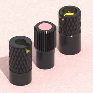 以下が含まれることがあります： さまざまなトップデザインの黒いボトルストッパーが3つ。1つはピンクのトップ、もう1つはダイヤモンドパターン、3つ目は黄色の内側を持つダイヤモンドパターンです。ストッパーは薄いピンク色の表面にあります。