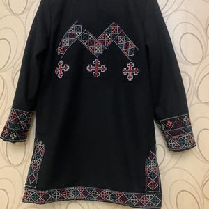Puede incluir: Chaqueta negra de manga larga con coloridos patrones geom&eacute;tricos bordados en la espalda y las mangas. El bordado presenta un patr&oacute;n repetitivo de cruces y diamantes.
