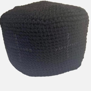 Może przedstawiać: Czarna czapka z dzianiny z fakturą i subtelnym wzorem krzyża.