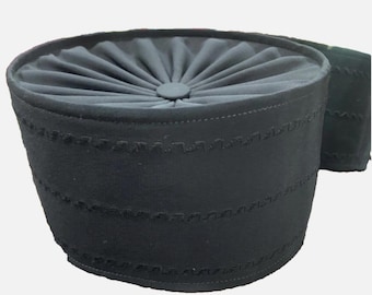 May include: A black fabric hat with a pleated top and a decorative stitched design around the brim.