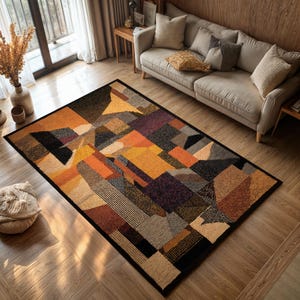 Peut inclure: Un tapis rectangulaire avec un motif géométrique dans les tons orange, jaune, marron, noir et violet. Le tapis a une bordure noire et est posé sur un sol en bois. Le design du tapis présente diverses formes et textures.