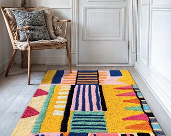 May include: A colorful geometric patterned rug with a yellow background. The rug has a variety of shapes and colors, including pink, blue, green, orange, and black.