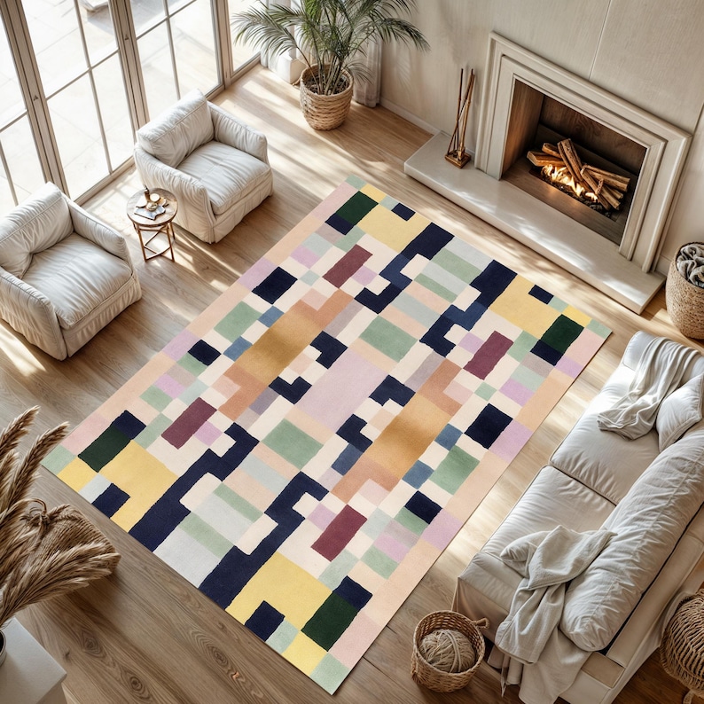 May include: A rectangular area rug with a geometric pattern in a variety of colors, including yellow, blue, green, and purple. The rug is placed in a living room setting with white armchairs, a sofa, and a fireplace.