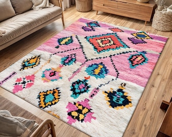 May include: A colorful, hand-woven rug with a pink, white, and blue geometric pattern. The rug has a traditional Moroccan design with intricate details.