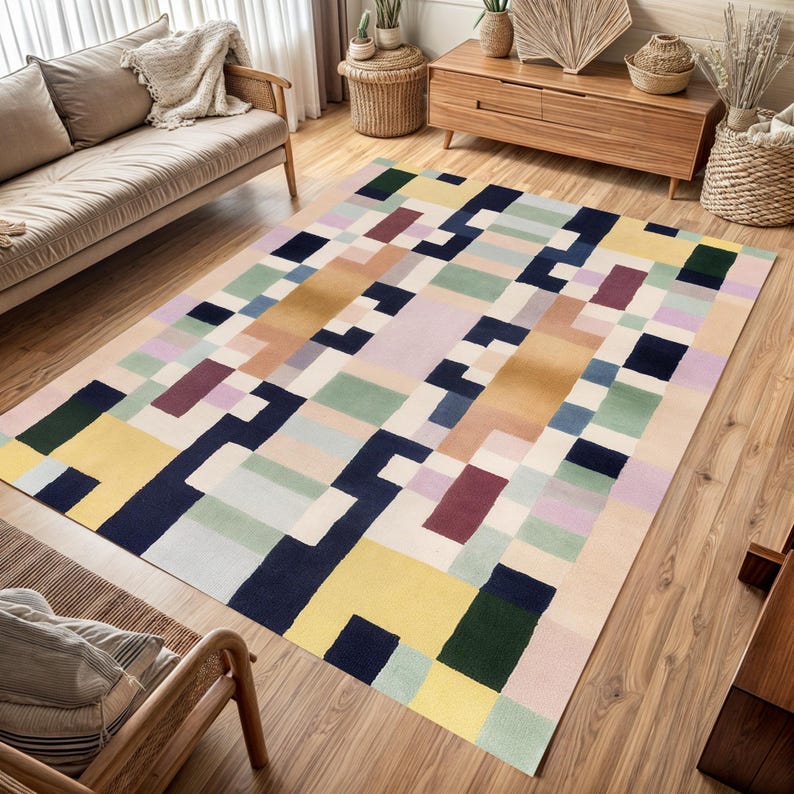 May include: A rectangular area rug with a geometric pattern in a variety of colors, including yellow, navy, green, and purple. The rug is placed on a hardwood floor in a living room setting. The design features a block-like pattern.