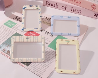 May include: Four plastic ID card holders with different patterns. Each holder has a clear plastic window for inserting an ID card. The patterns include blue and white bows, yellow and brown bows, and a light blue and white striped pattern.