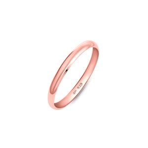 May include: A polished rose gold-toned ring with a smooth, rounded band. The interior of the band features a clear engraving that reads 925, indicating the metal composition. The ring has a simple, continuous circular design with a reflective finish.