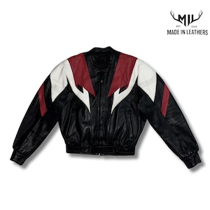 Könnte beinhalten: Eine schwarze Lederjacke mit einem Color-Block-Design aus weißen und roten Einsätzen an Brust und Ärmeln. Die Jacke verfügt über einen Frontreißverschluss, lange Ärmel mit gerippten Bündchen und ein Logo oben rechts mit der Aufschrift MIL EST. 1999 MADE IN LEATHERS.