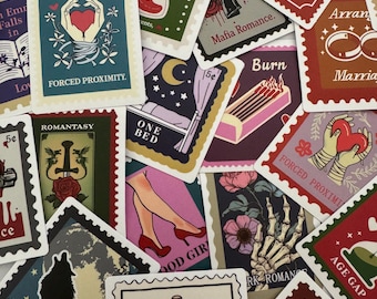 Puede incluir: Una colección de pegatinas decorativas con diseños de sellos postales vintage. Las pegatinas presentan varias ilustraciones, incluyendo un corazón, un reloj de arena y una mano de esqueleto, con textos como "Burn", "Forced Proximity" y "Enemies to Lovers."