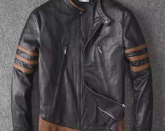 Puede incluir: Chaqueta de cuero negra con detalles marrones en las mangas y el dobladillo. Tiene cuello alzado, cierre de cremallera y dos bolsillos con cremallera. Las mangas tienen tres rayas marrones.