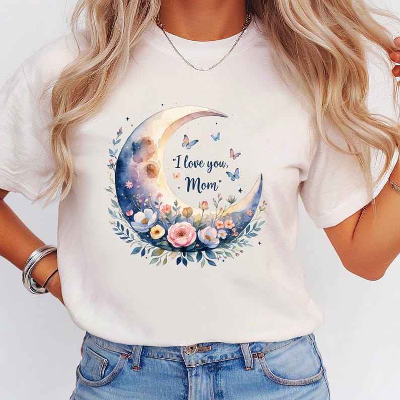 May include: White t-shirt featuring a watercolor design of a crescent moon with floral accents and butterflies. The moon is filled with shades of blue, purple, and gold, and the text "I love you, Mom" is printed on the moon.