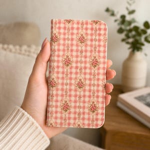 May include: A rectangular phone case featuring a pink and white gingham check pattern overlaid with vertical columns of small, detailed floral bouquets in shades of pink, green, and cream, with rounded top corners and a slim, flat profile.