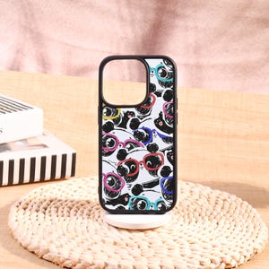 May include: Black phone case with a repeating pattern of panda faces wearing colorful glasses. The case has a black border and a cutout for the camera. The design includes pink, blue, yellow, and red glasses.