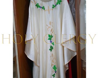 May include: Ivory-colored liturgical vestment with gold trim and embroidered details. The garment features a cross and floral patterns in green, purple, and gold. The text "HOLY CLERGY" is visible in gold.