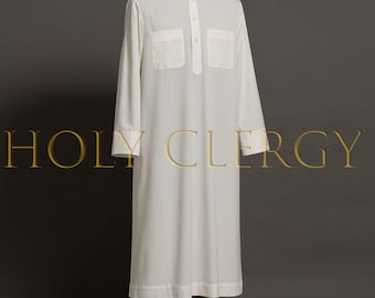 Può includere: Una veste bianca da clero con maniche lunghe, colletto alla coreana e due tasche sul petto. La veste ha una chiusura frontale con bottoni ed è esposta su un manichino. Il testo "HOLY CLERGY" è visibile in oro.