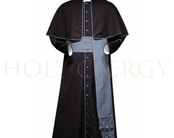 May include: A black clerical cassock with a matching cape, accented with light gray trim. A light gray sash and a white collar complete the ensemble. The cassock is buttoned down the front. The text "HOLY CLERGY" is visible in the background.