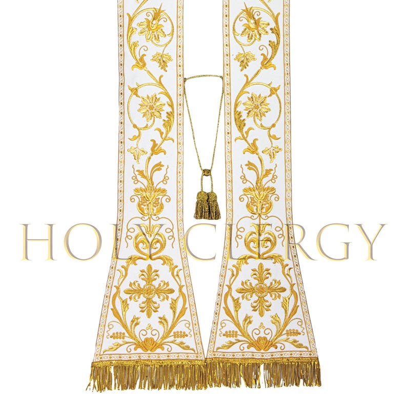 May include: White liturgical stole with gold floral embroidery and a gold tassel cord. The stole features intricate designs, including flowers and crosses, and is trimmed with a gold fringe. The word "HOLY CLERGY" is printed at the bottom of the stole.