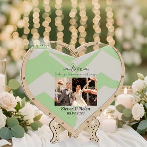 May include: Heart-shaped wedding sand ceremony set with a photo of a couple and the text "love today tomorrow always". The wooden frame has a green and white chevron pattern. The names "Steven & Helen" and the date "09.09.2025" are also displayed.