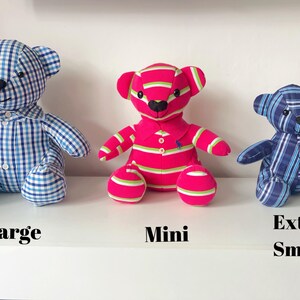 May include: Three stuffed teddy bears in different sizes. The large bear is blue and white checkered. The mini bear is pink with green and white stripes. The extra small bear is blue and white striped. Text on the shelf reads "Large", "Mini", and "Extra Small".