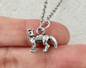 May include: A silver-colored pendant necklace featuring a detailed wolf charm. The wolf is depicted in a standing pose with intricate fur detailing. The necklace chain is also silver and appears delicate.