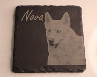 Könnte beinhalten: Ein schwarzer Schieferuntersetzer mit einem weißen Hund, der in die Oberfläche geätzt ist. Der Name des Hundes, "Nova", steht über dem Hund.