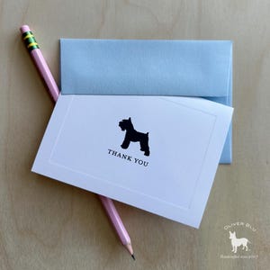 Puede incluir: Tarjeta de agradecimiento blanca con una silueta de perro negro y la frase "THANK YOU". Un sobre azul claro está detrás de la tarjeta. Un lápiz rosa con una goma verde descansa sobre la tarjeta. El logotipo de Oliver Blu está en la esquina inferior derecha.