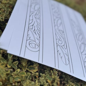 May include: A sheet of paper featuring four distinct black and white floral border designs. The patterns are elaborate and detailed, ideal for adding a touch of sophistication to any project.
