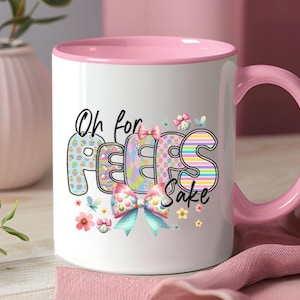 Może przedstawiać: Biały kubek ceramiczny z różowym rantem i uchwytem. Kubek ma kolorową grafikę z napisem "Oh for Peeps Sake" z kokardką i kwiatami.