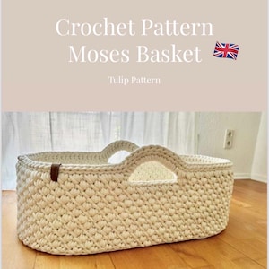 Könnte beinhalten: Ein cremefarbener Moseskorb aus Häkelarbeit mit zwei bogenförmigen Griffen. Der Korb hat ein strukturiertes Stichmuster und ein braunes Lederdetail. Der Text "Crochet Pattern Moses Basket" befindet sich oben im Bild.