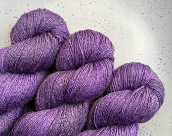Può includere: Tre gomitoli di filato viola con una trama macchiettata.