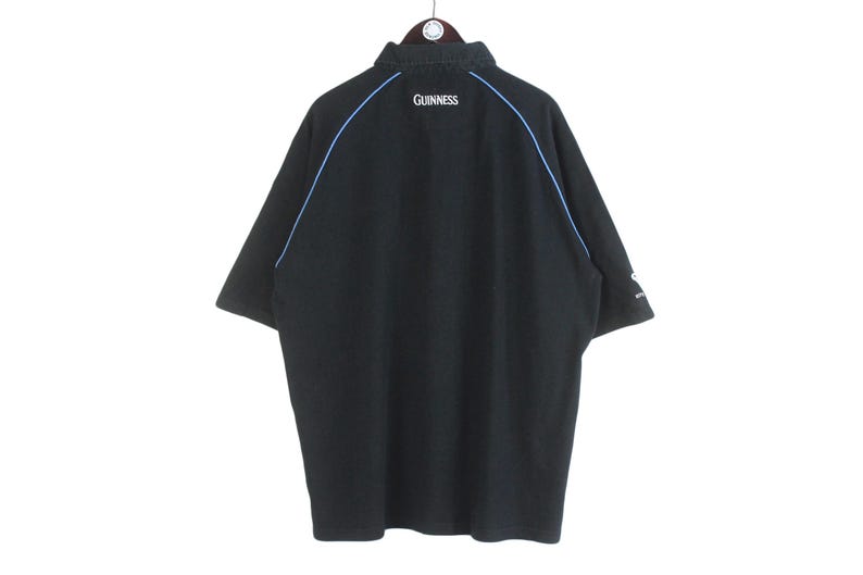 May include: Black short-sleeved polo shirt with blue trim and the word "GUINNESS" embroidered on the back.